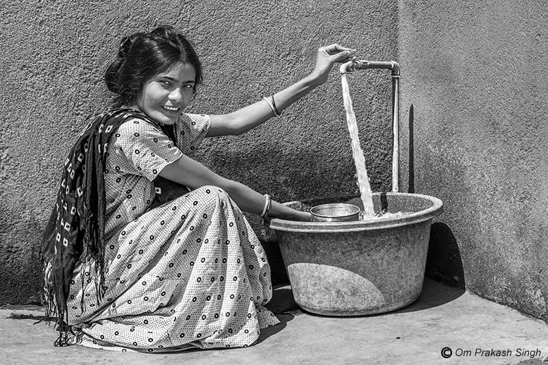 A rural lady happily managing her household chores using the Jal Jeevan Mission (JJM) water supply in her courtyard in Seraikela-Kharsawan district, Jharkhand, India